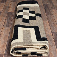 Load image into Gallery viewer, Folded geometric-patterned rug on a wooden floor