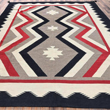 Load image into Gallery viewer, Geometric patterned rug with red, black, gray, and white colors on a wooden floor.