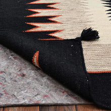 Load image into Gallery viewer, Close-up of a black and orange patterned rug on a wooden floor.