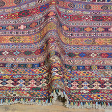 Load image into Gallery viewer, Multicolored patterned fabric with tassels on a wooden surface