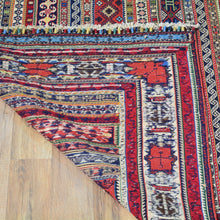 Load image into Gallery viewer, Close-up of a colorful patterned rug on a wooden floor
