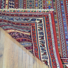 Load image into Gallery viewer, Close-up of a colorful patterned rug on a wooden floor