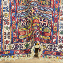 Load image into Gallery viewer, Colorful patterned fabric with tassels on a wooden surface